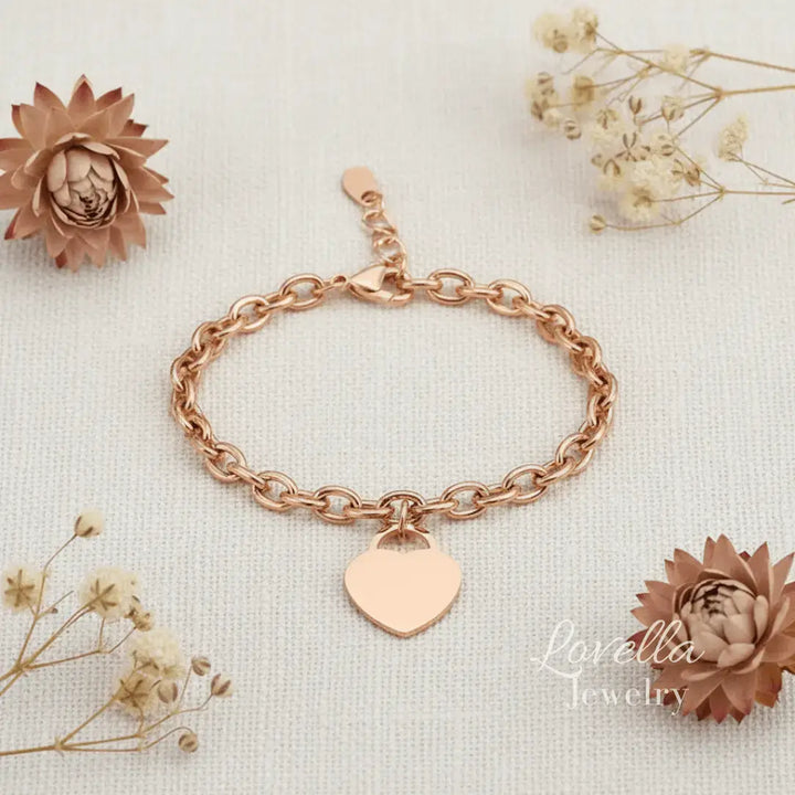 Rose gold bracelet with a heart charm on a light background with decorative flowers.