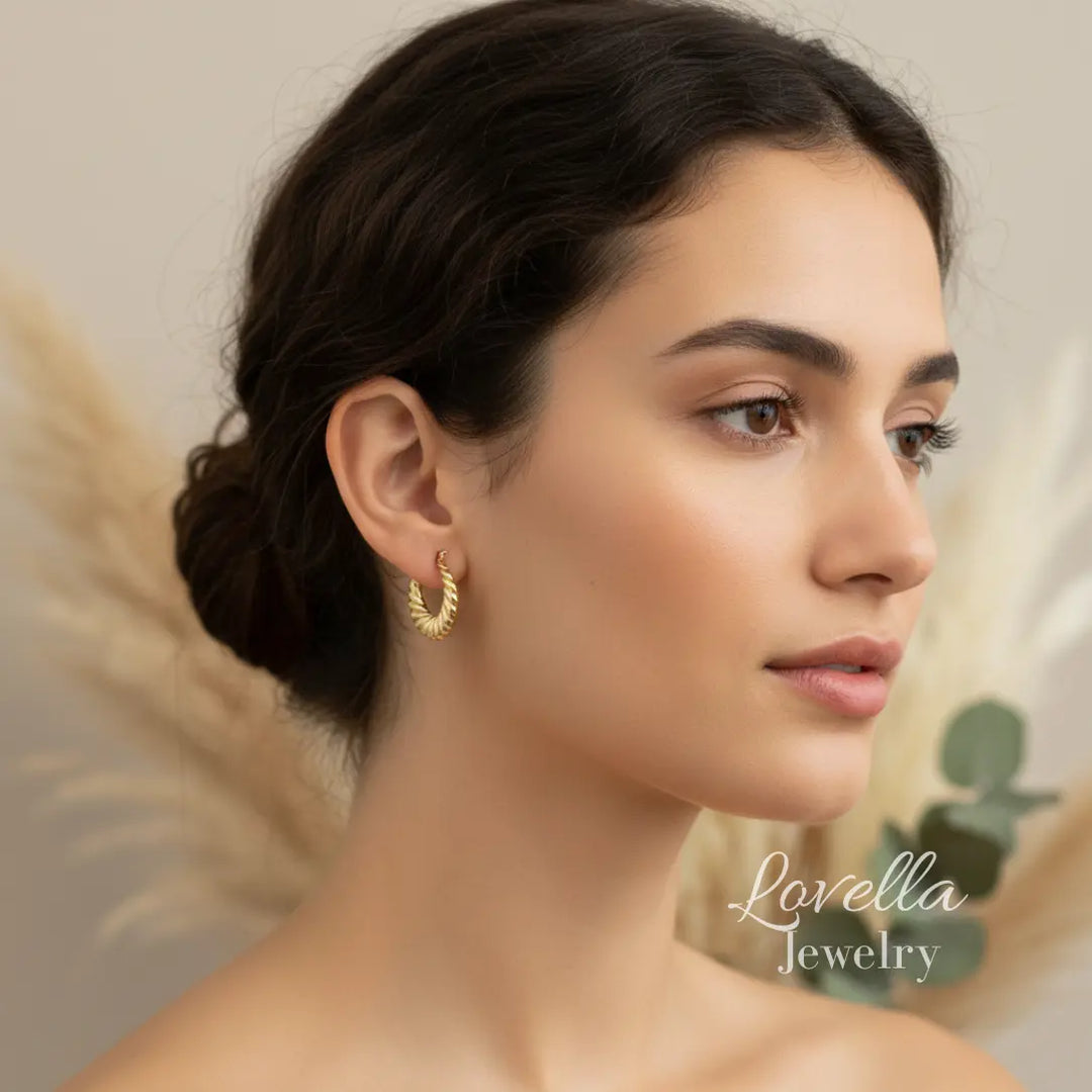 Woman wearing gold earrings with a blurred background and 'Lovella Jewelry' branding.