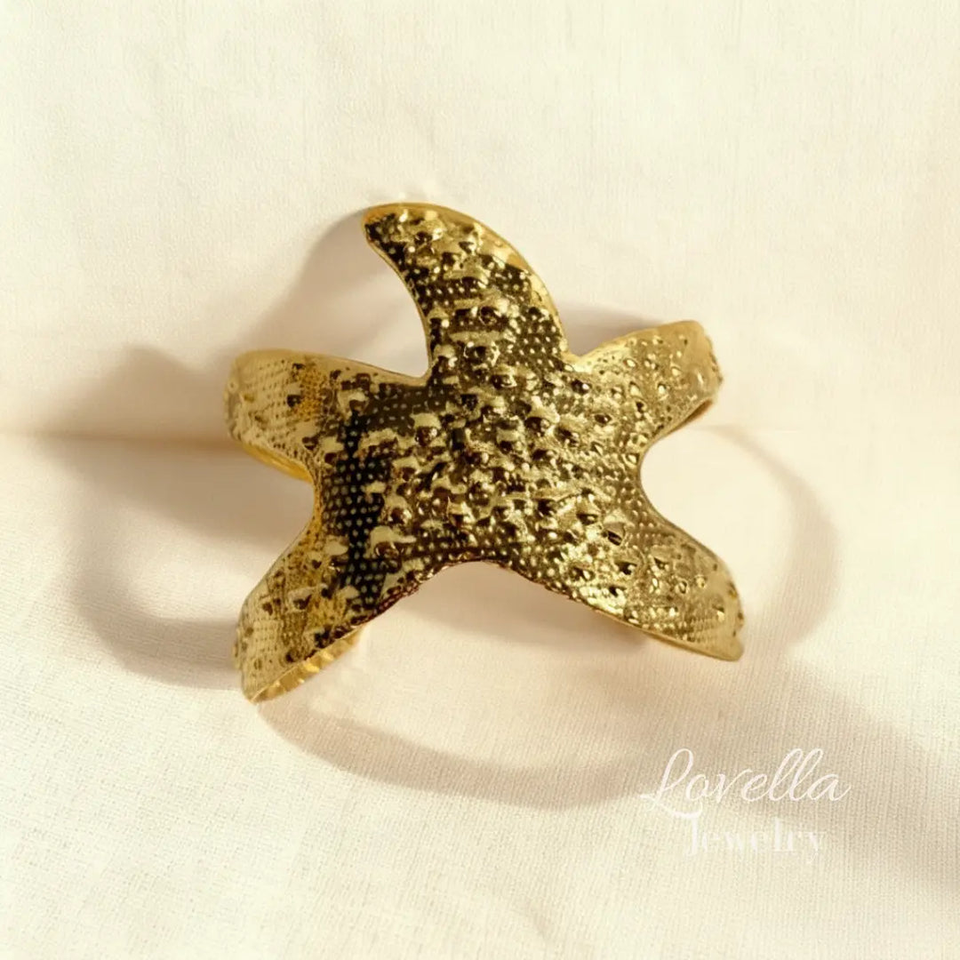 Gold starfish-shaped object on a beige background with 'Lovella' branding.