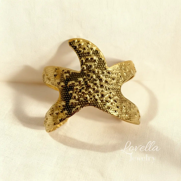 Gold starfish-shaped object on a beige background with 'Lovella' branding.
