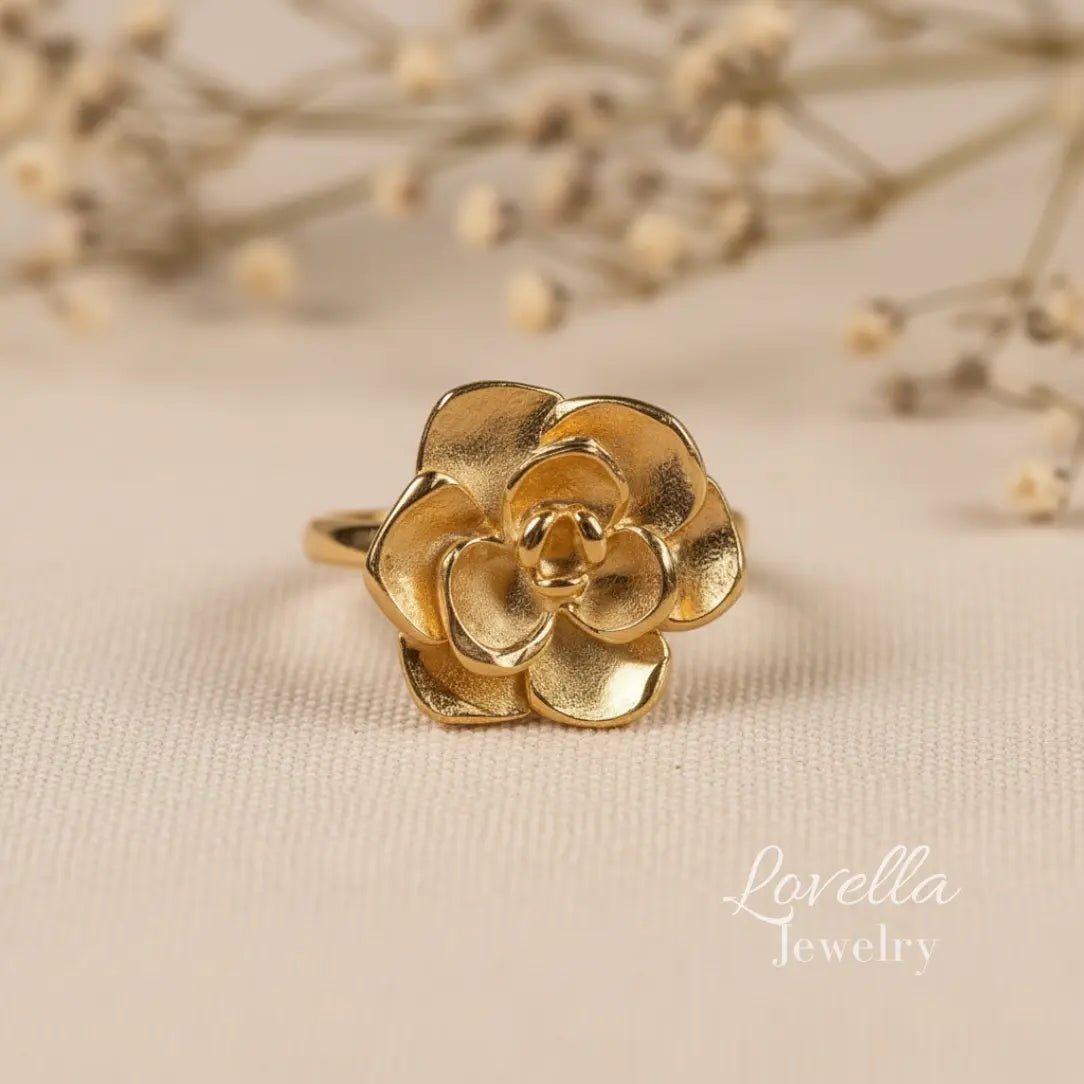 Gold flower-shaped ring on a beige fabric background with 'Lovella Jewelry' branding.