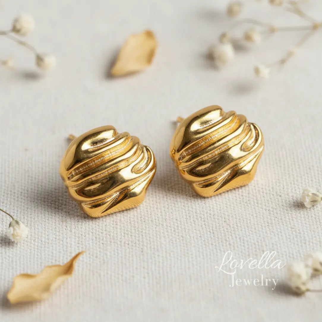 Gold chunky swirl stud earrings on cream linen background with dried flowers and Lovella Jewelry logo