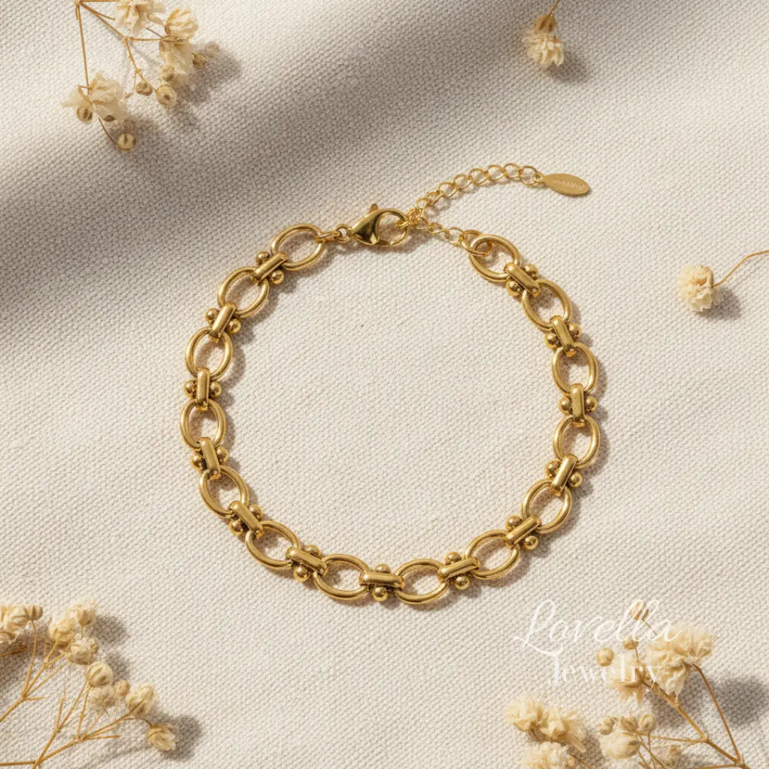 Gold chain bracelet on a light beige background with dried flowers