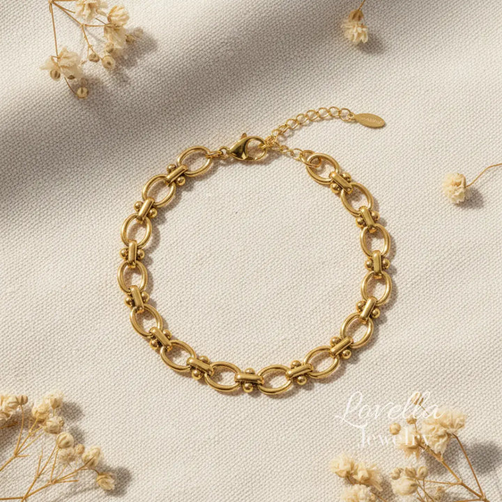 Gold chain bracelet on a light beige background with dried flowers