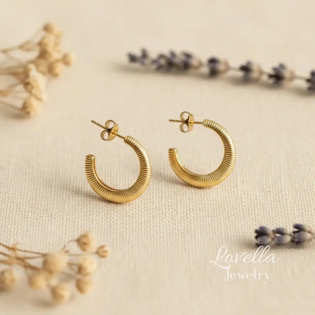 Gold hoop earrings on a beige surface with 'Lovella Jewelry' branding.