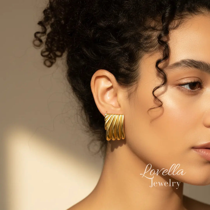 Woman wearing gold earrings with 'Lovella Jewelry' branding