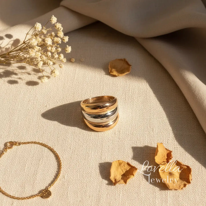 Three Tone ring and bracelet on a textured surface with dried flowers and leaves, Lovella Jewelry branding visible.