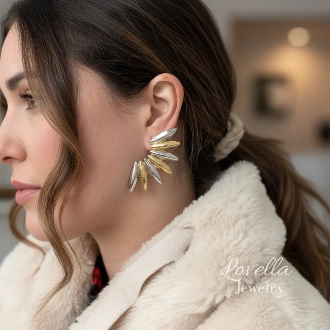 Woman wearing gold and silver earrings with a blurred indoor background, featuring Lovella Jewelry logo.