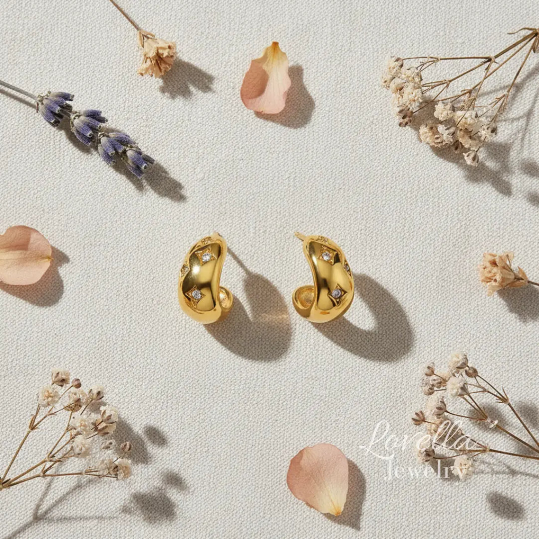 Gold earrings on a light surface with dried flowers and petals