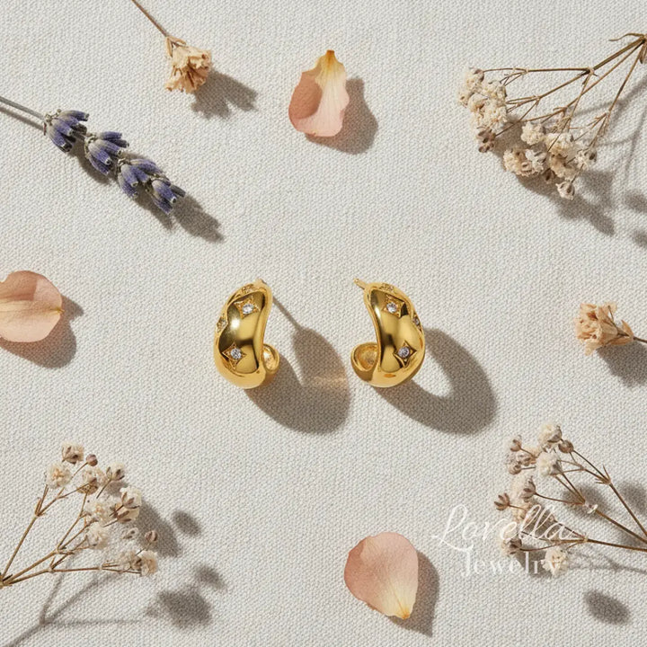 Gold earrings on a light surface with dried flowers and petals