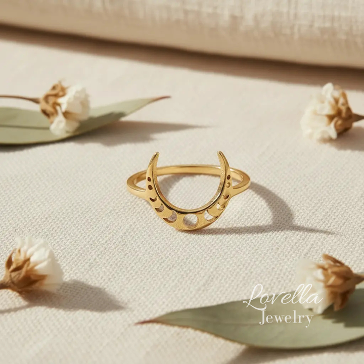 Gold ring with a unique design on a beige surface with dried flowers, featuring 'Lovella Jewelry'.