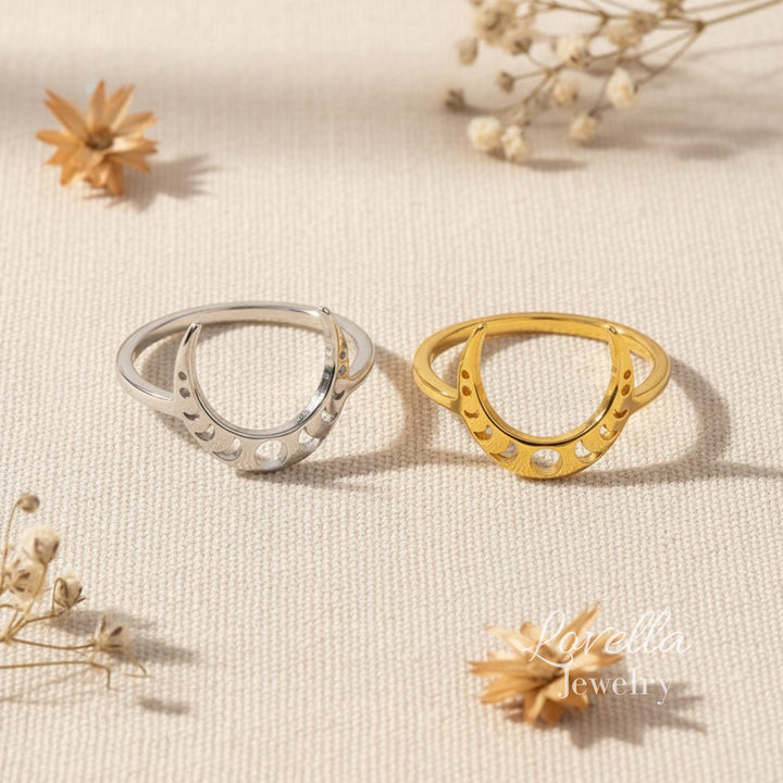 Two rings, one silver and one gold, on a textured beige surface with dried flowers.