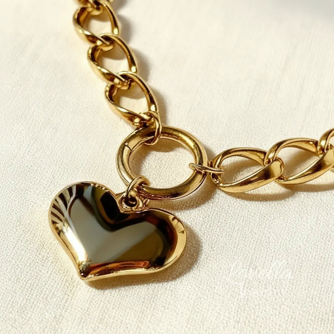 Gold chain bracelet with a heart-shaped charm on a light background