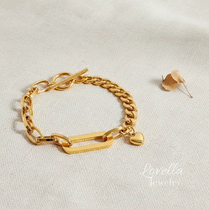 Gold chain bracelet with a tag and matching earrings on a light background