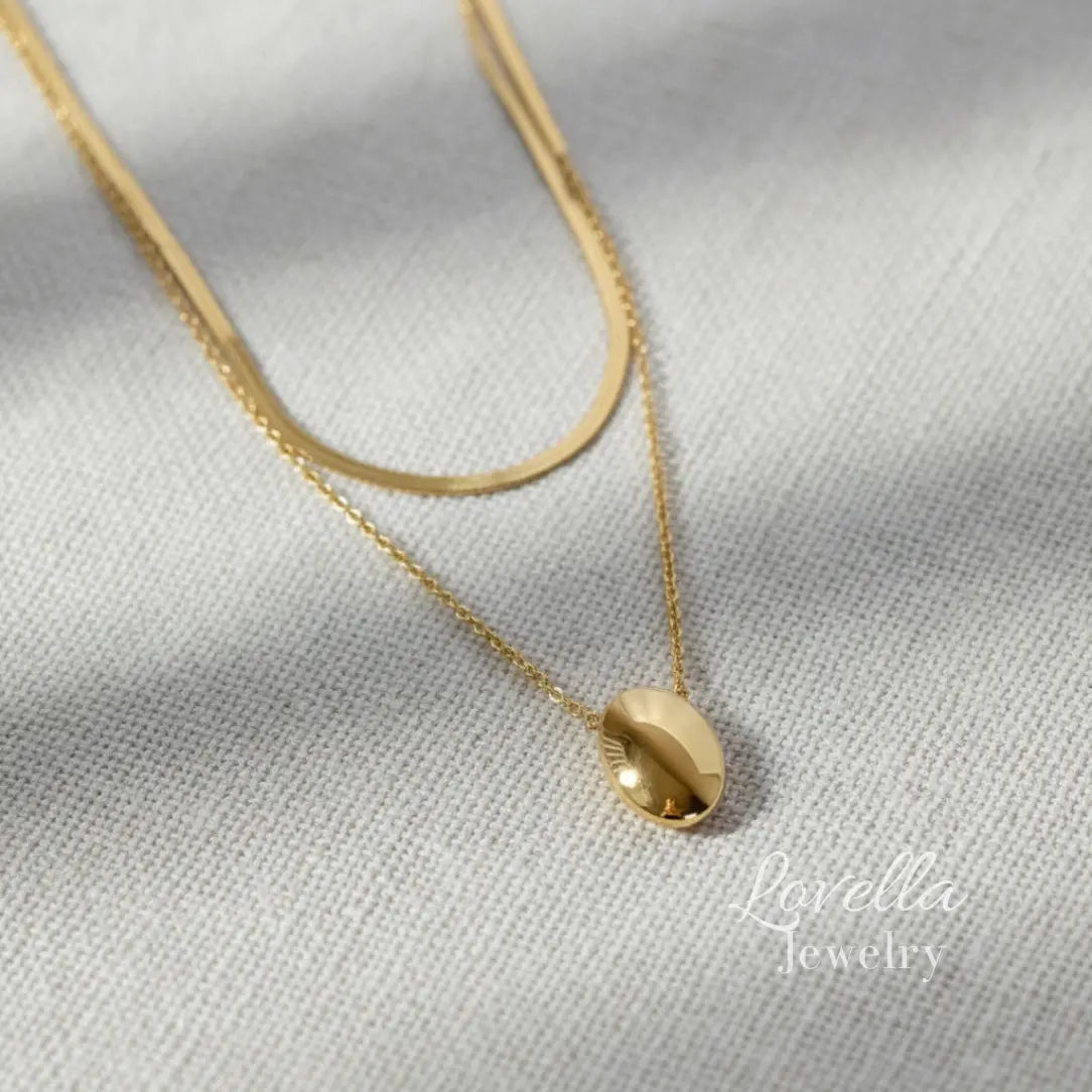 Gold necklace with a pendant on a light gray fabric background