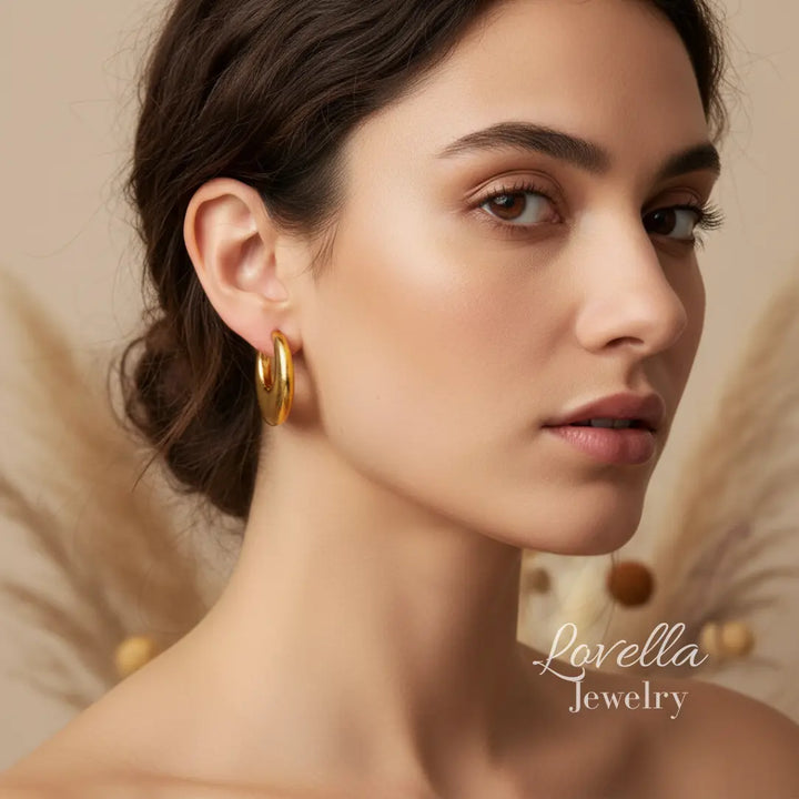 Woman wearing gold hoop earrings with 'Lovella Jewelry' branding.