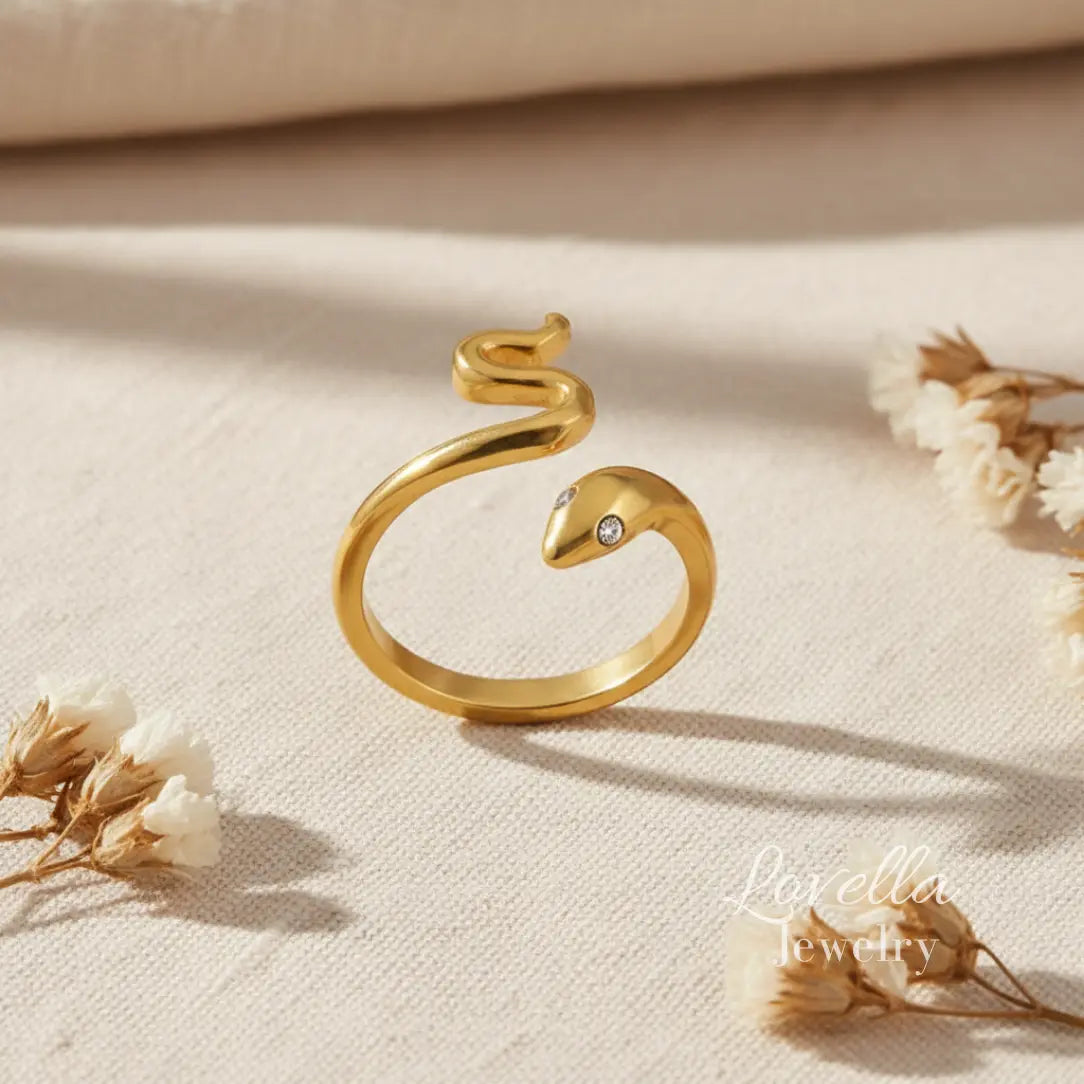 Gold snake-shaped ring with gemstones on a beige fabric background