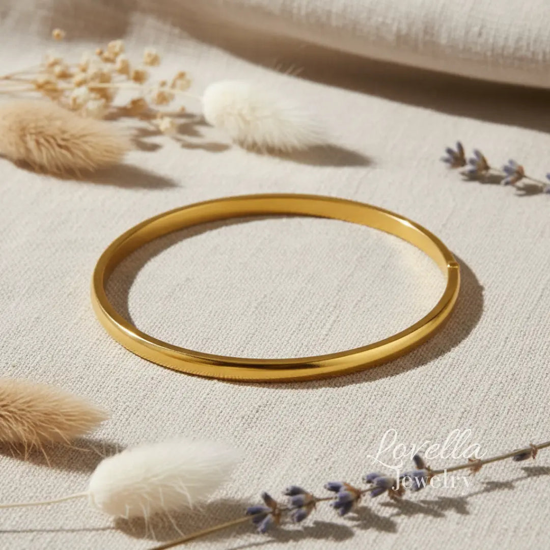 Gold bracelet on a textured beige surface with dried plants