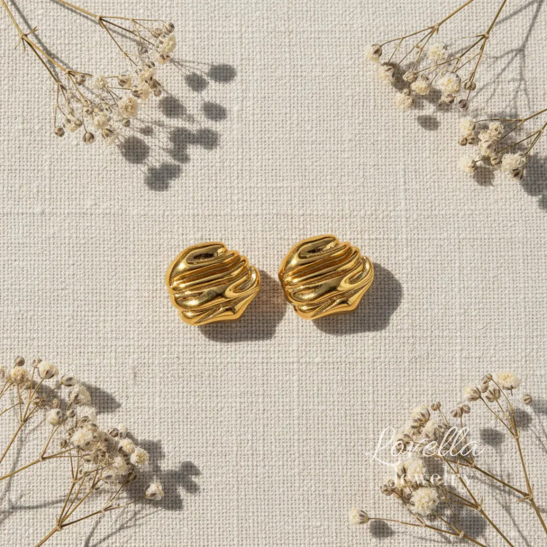 Gold chunky swirl stud earrings on cream linen background with dried flowers and Lovella Jewelry logo