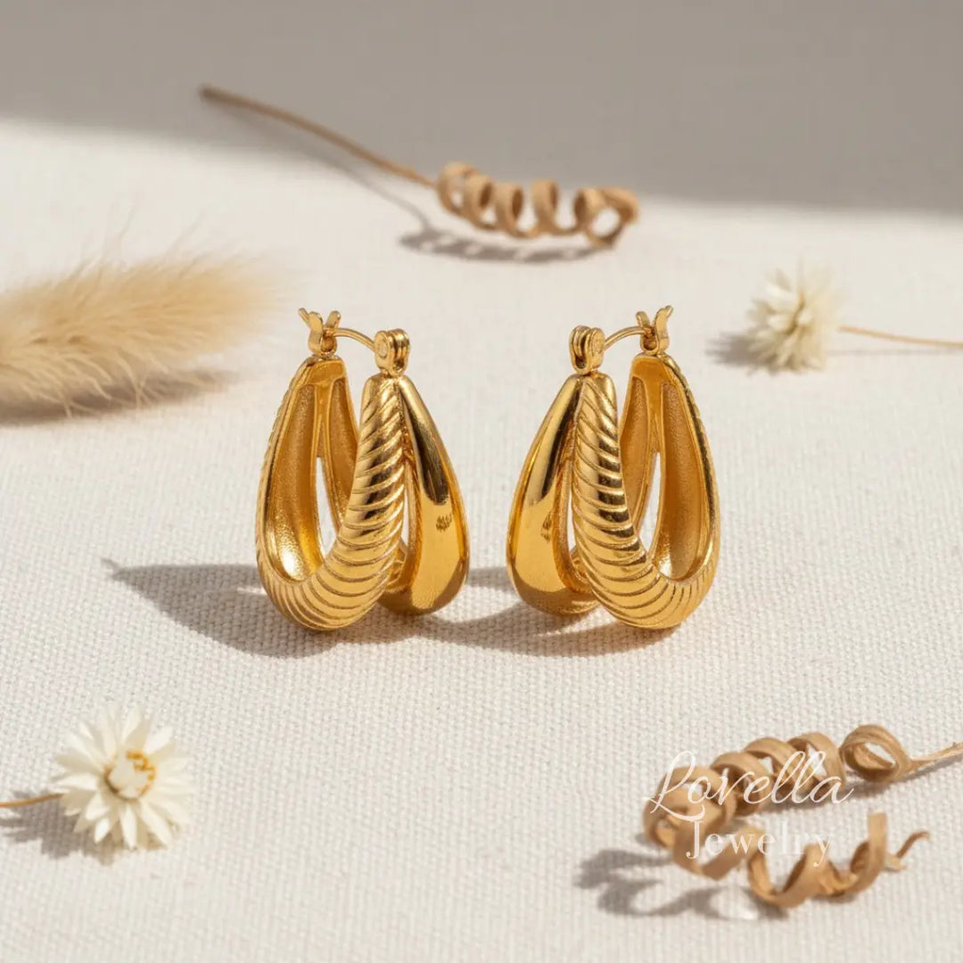 Gold hoop earrings on a light surface with minimal background