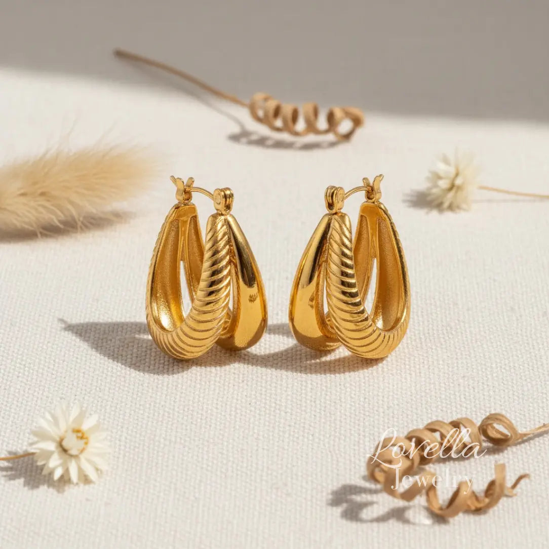 Gold hoop earrings on a light surface with minimal background