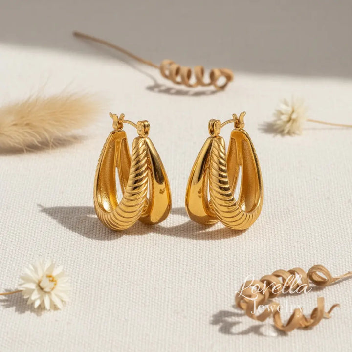 Gold hoop earrings on a light surface with minimal background