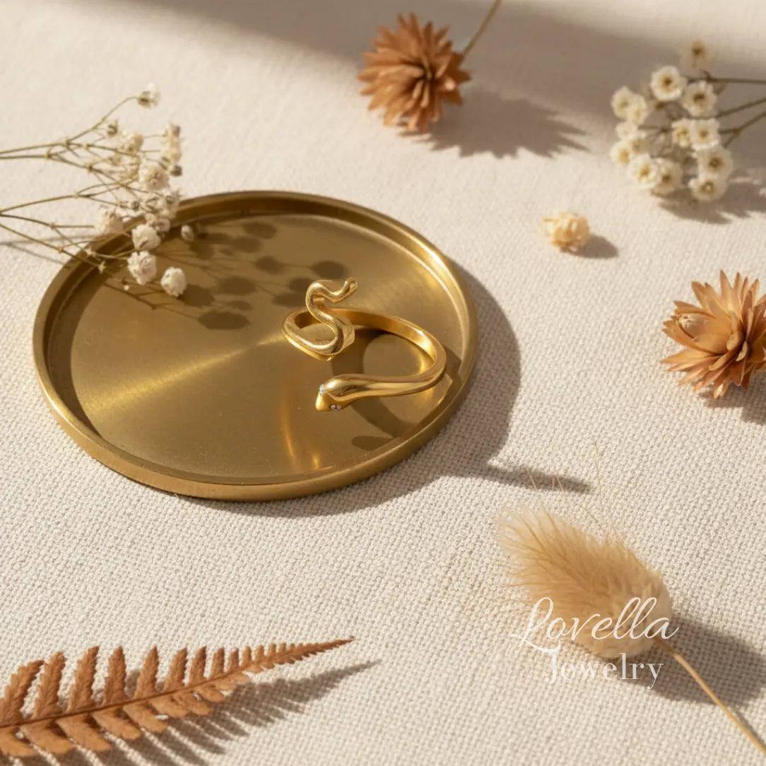 Gold ring on a decorative tray with dried flowers and leaves on a light background