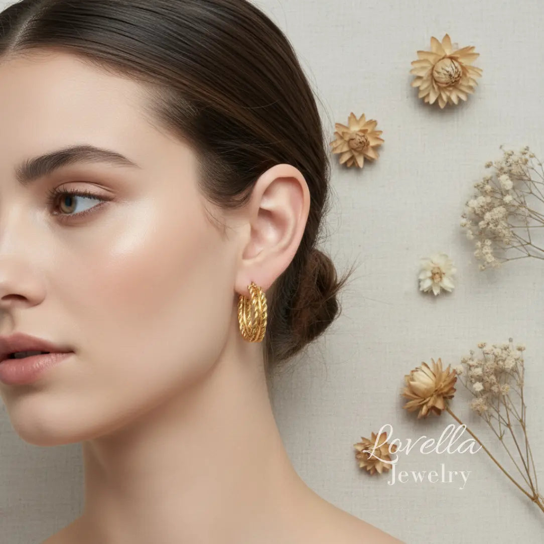 Woman wearing gold earrings with decorative flowers in the background, featuring Lovella Jewelry.