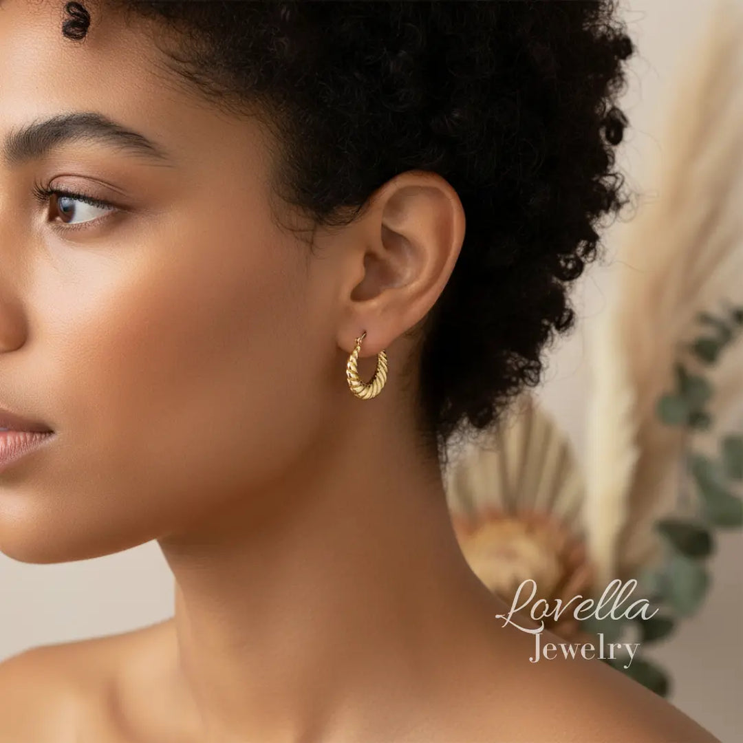 Close-up of a woman wearing gold hoop earrings with 'Lovella Jewelry' branding.