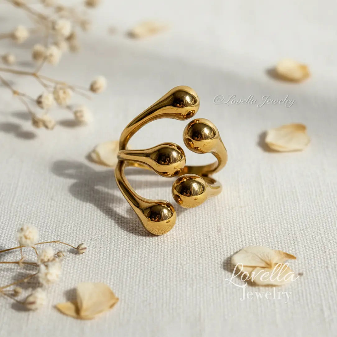 Gold ring with a unique design on a light background with dried flowers.