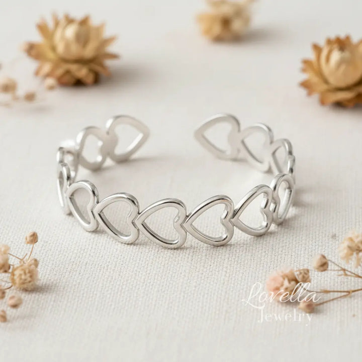 Silver heart-shaped bracelet on a light background with dried flowers.