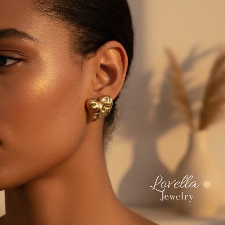 Close-up of a woman wearing gold earrings with 'Lovella Jewelry' branding.