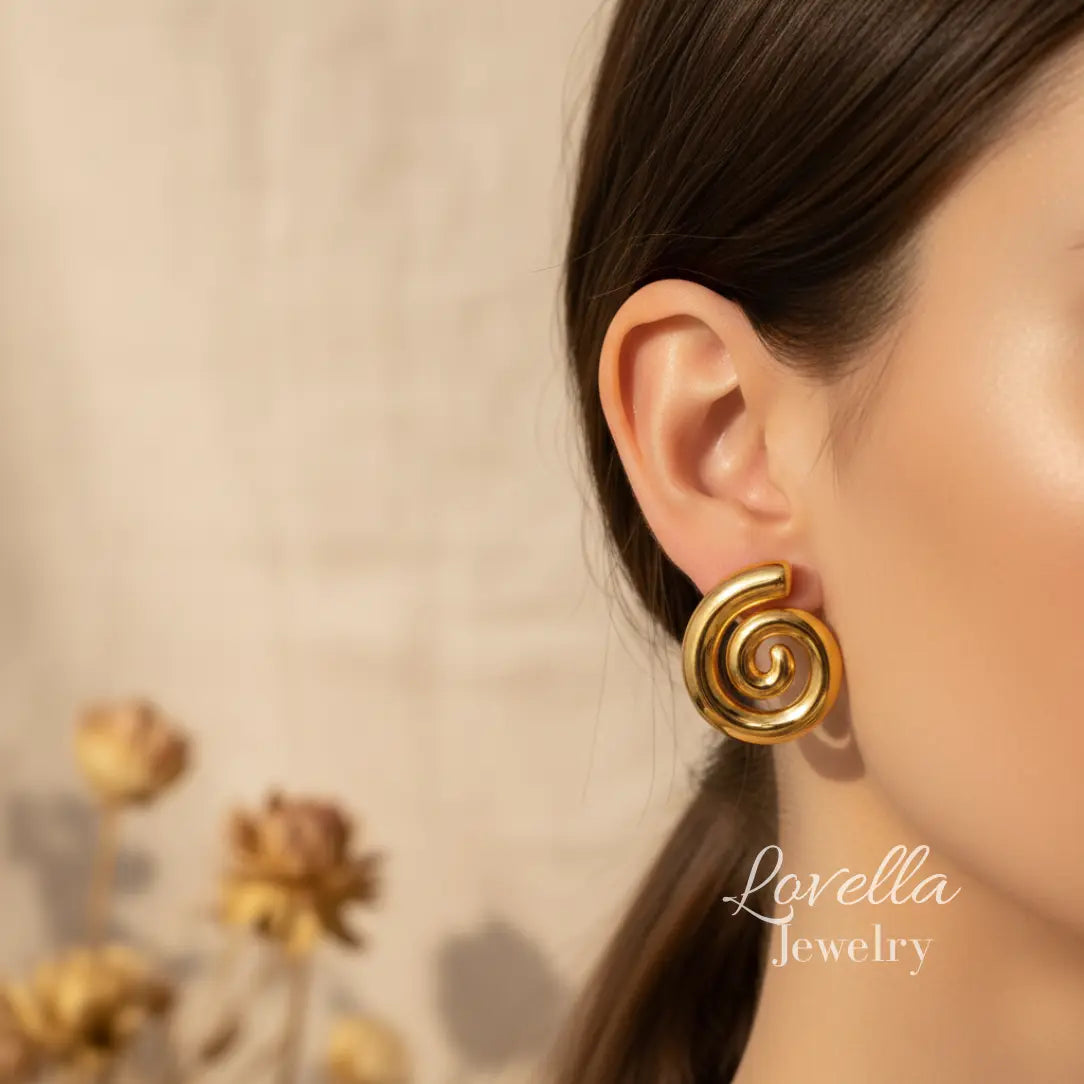 Gold spiral earring worn by a model with 'Lovella Jewelry' branding.