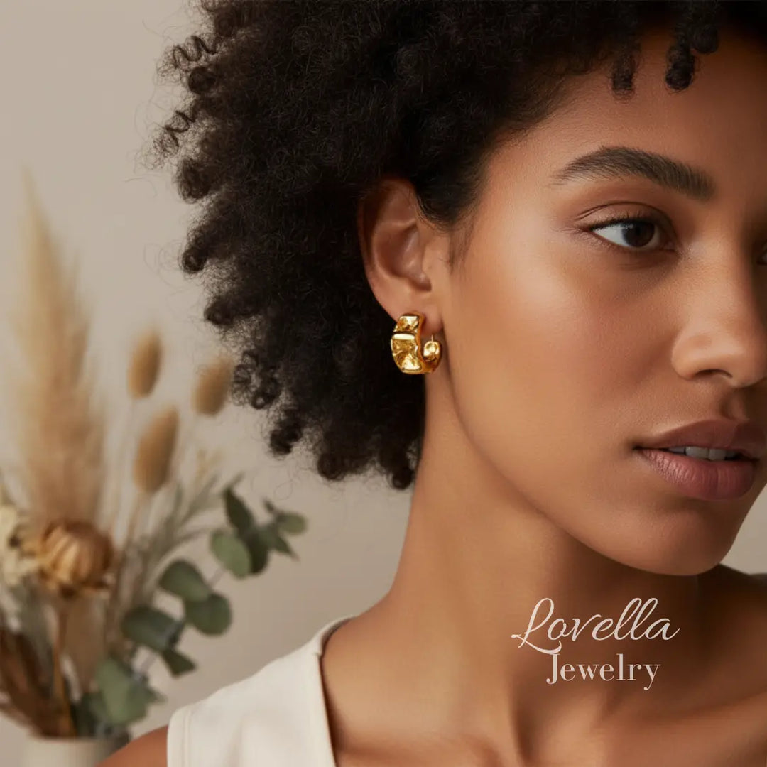 Woman wearing gold earrings with a blurred background and 'Lovella Jewelry' branding.