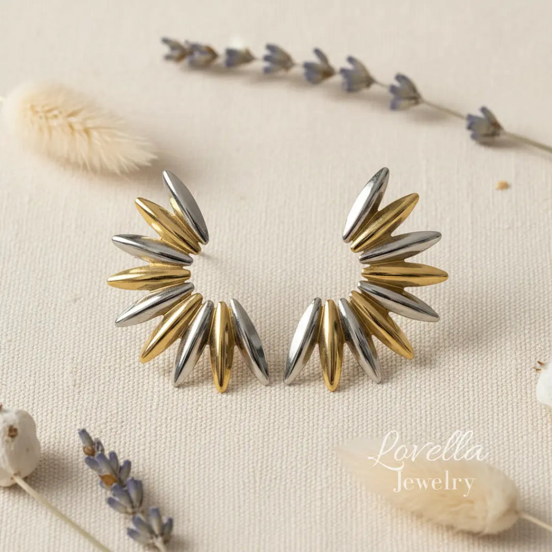 Pair of gold and silver spike earrings on a neutral background with floral elements.