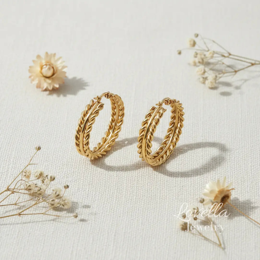 Gold hoop earrings on a light background with dried flowers.