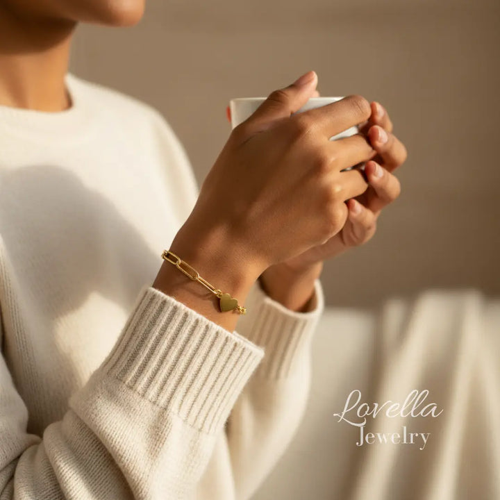 Person wearing a gold bracelet holding a mug with 'Lovella Jewelry' branding.