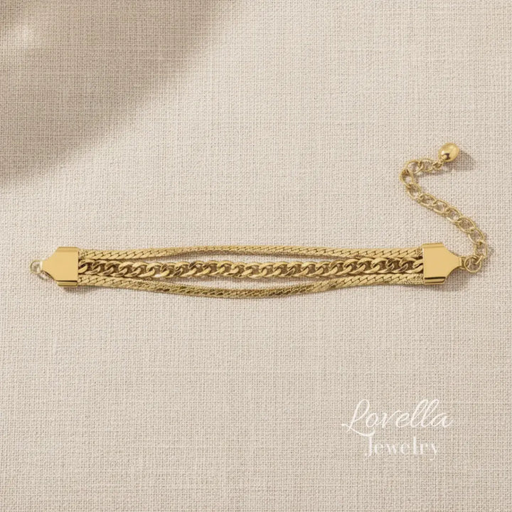 Gold chain bracelet on a beige fabric background with 'Lovella Jewelry' branding.