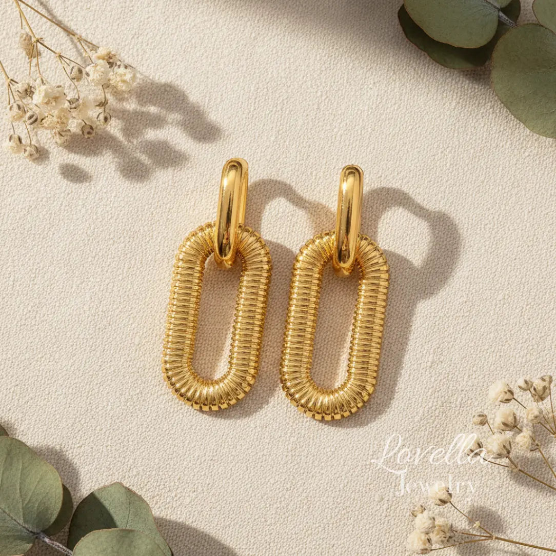 Gold hoop earrings on a light background with greenery