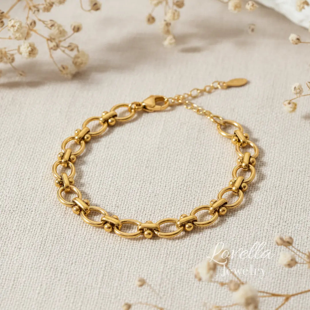 Gold bracelet on a light fabric background with dried flowers