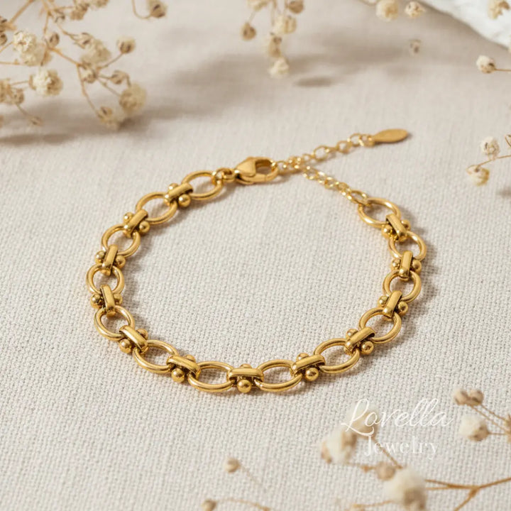 Gold bracelet on a light fabric background with dried flowers