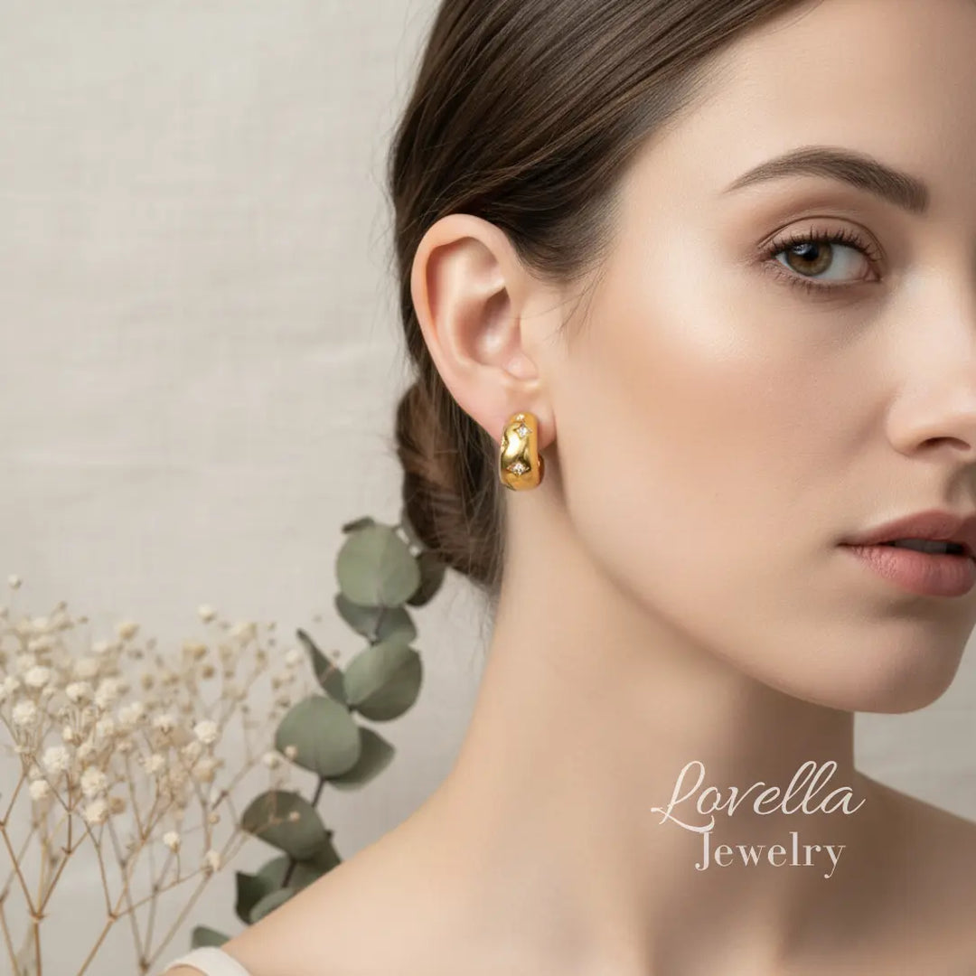 Woman wearing gold earrings with a neutral background and 'Lovella Jewelry' branding.