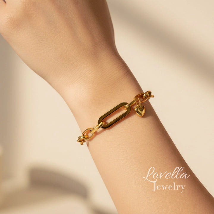 Gold bracelet on a wrist with 'Lovella Jewelry' branding on a beige background