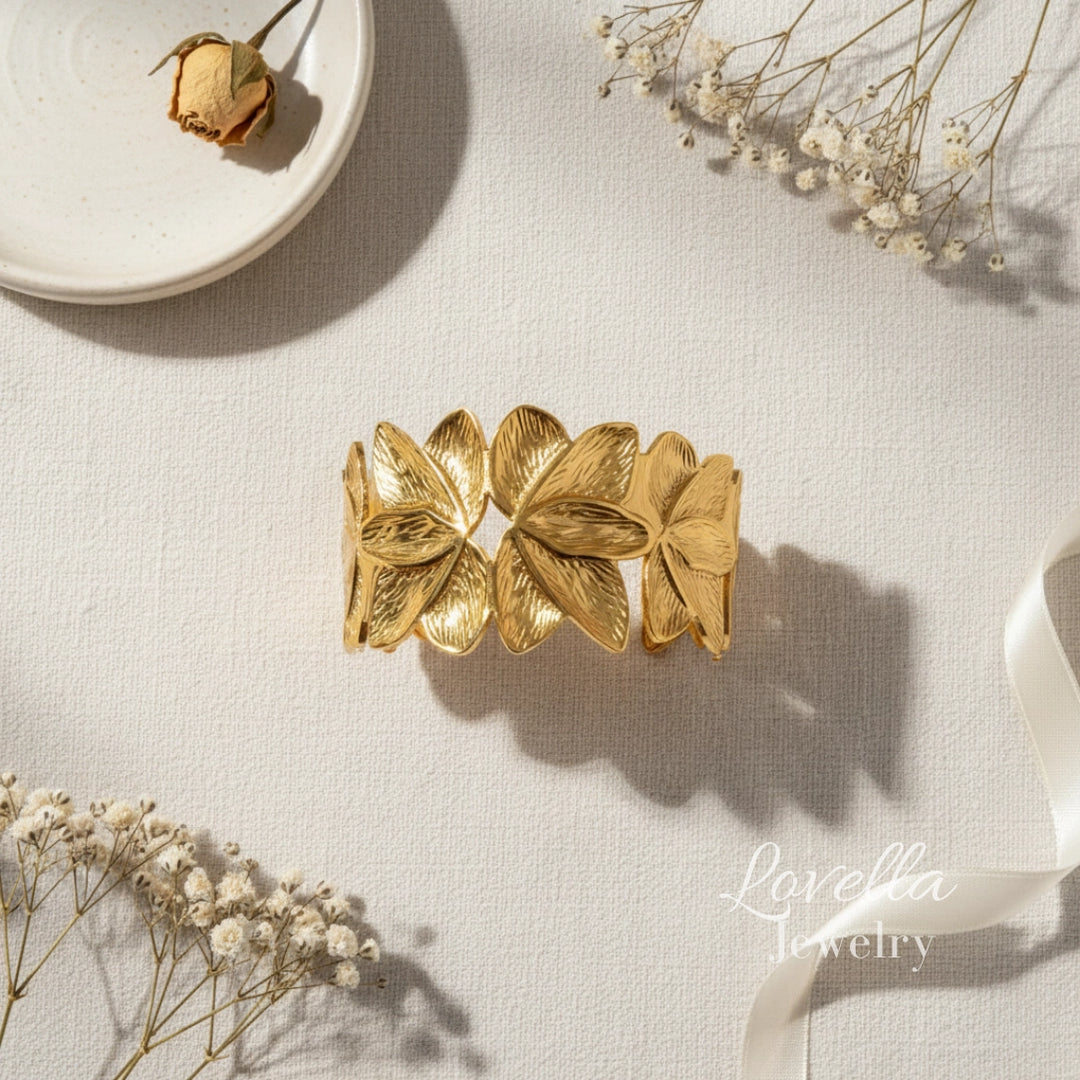 Gold leaf bracelet on a light surface with dried flowers