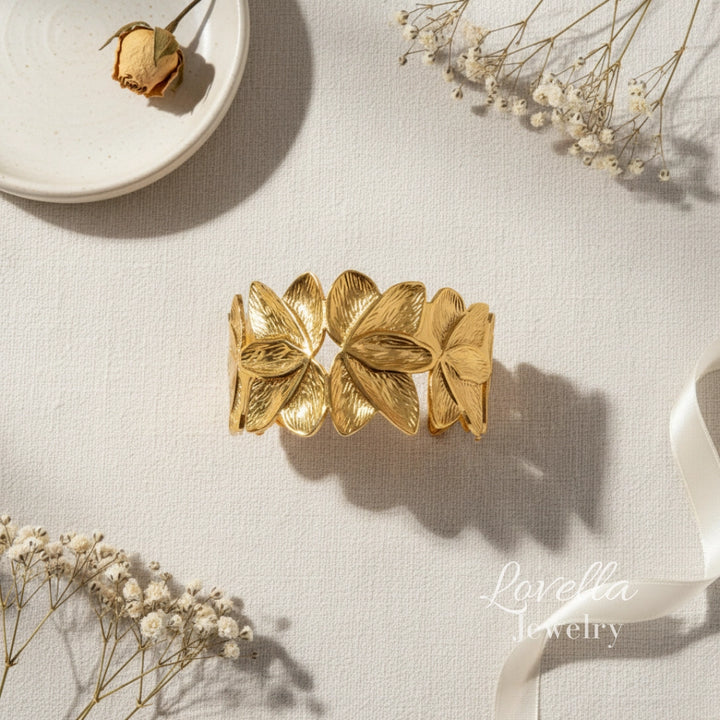 Gold leaf bracelet on a light surface with dried flowers
