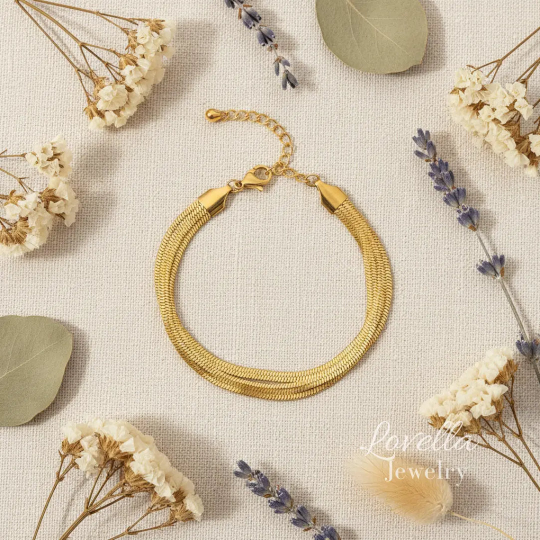Gold bracelet on a textured surface with dried flowers and leaves