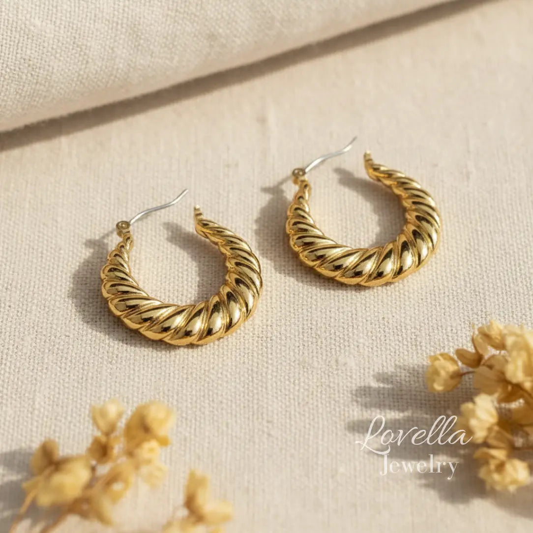 Gold hoop earrings on a beige fabric background with 'Lovella Jewelry' branding.