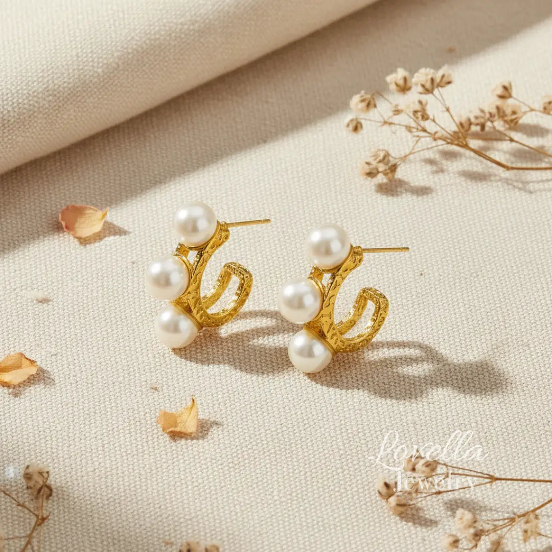 Gold earrings with pearls on a beige fabric background