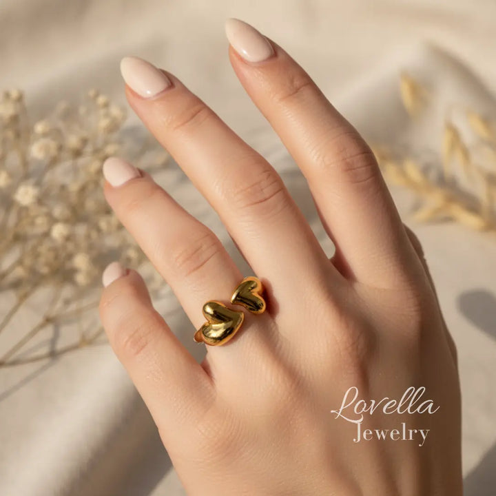 Gold heart-shaped ring on a hand with 'Lovella Jewelry' branding.
