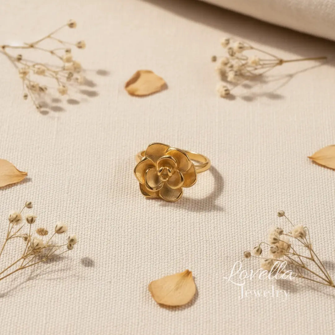 Gold flower-shaped ring on a beige fabric background with dried flowers.